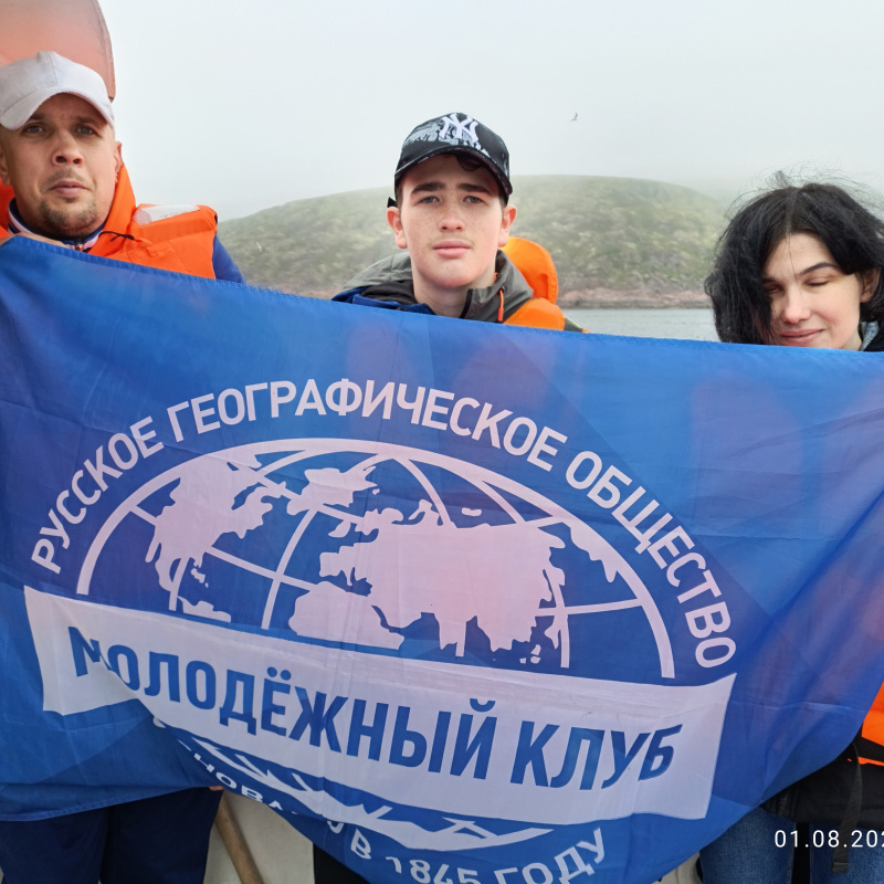 Слабовидящий Вячеслав, незрячая Надежда и волонтёр Андрей в ожидании китов Слабовидящий Вячеслав Дорофеев, незрячая Надежда Долматова и волонтёр Андрей Юрьев держат флаг РГО