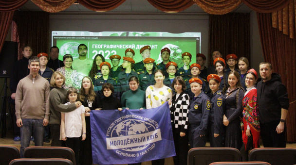 Участники Географического диктанта-2023 в актовом зале школы №340 Санкт-Петербурга с флагом МК РГО